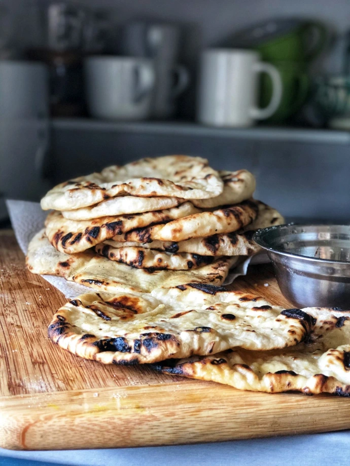 a pile of pita bread sitting on top of a wooden cutting board
